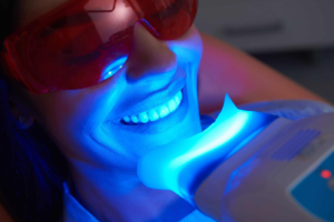 Patient undergoing professional teeth whitening with an LED light during an in-office dental treatment.
